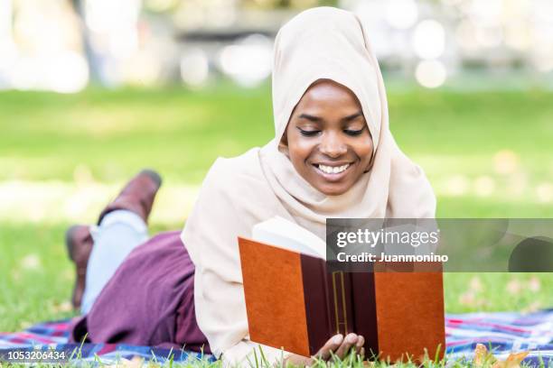 schwarze junge muslimin ein buch zu lesen - sénégal migration stock-fotos und bilder