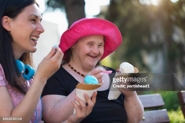 vrouw met het syndroom van down en haar vriend eten van ijs en plezier - down syndrome care stockfoto's en -beelden