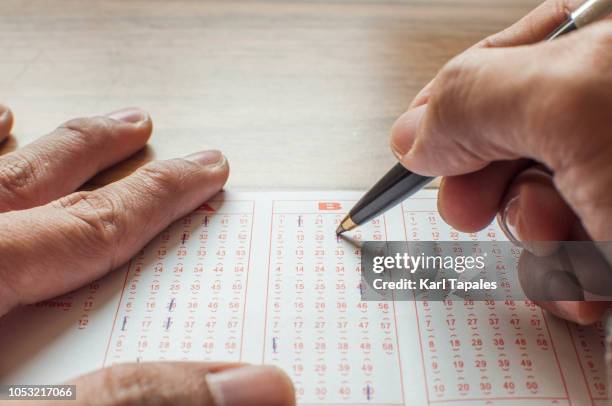 close up of hands filling up a lottery ticket form - jackpot stock pictures, royalty-free photos & images