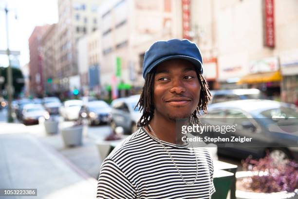 portrait of young man on city street - dreadlocks stockfoto's en -beelden