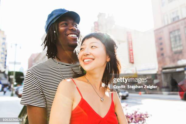 young couple on city street - young couples fotografías e imágenes de stock