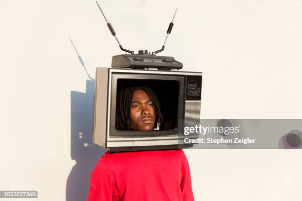 portrait of a young man with a tv set on his head - televisiepresentator stockfoto's en -beelden