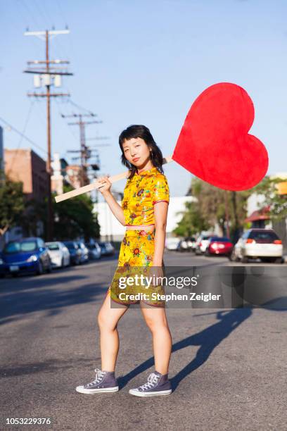 young woman holding a large cardboard heart sign - charming stock pictures, royalty-free photos & images