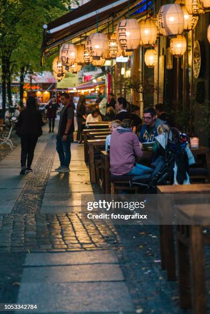 nightlife in berlin: street in kreuzberg with sidewalk coffees and restaurants. - kreuzberg stock pictures, royalty-free photos & images