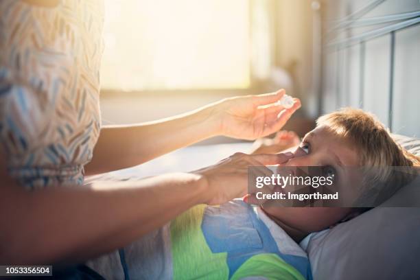 aplicar gotas en los ojos del hijo de la madre - bloodshot fotografías e imágenes de stock