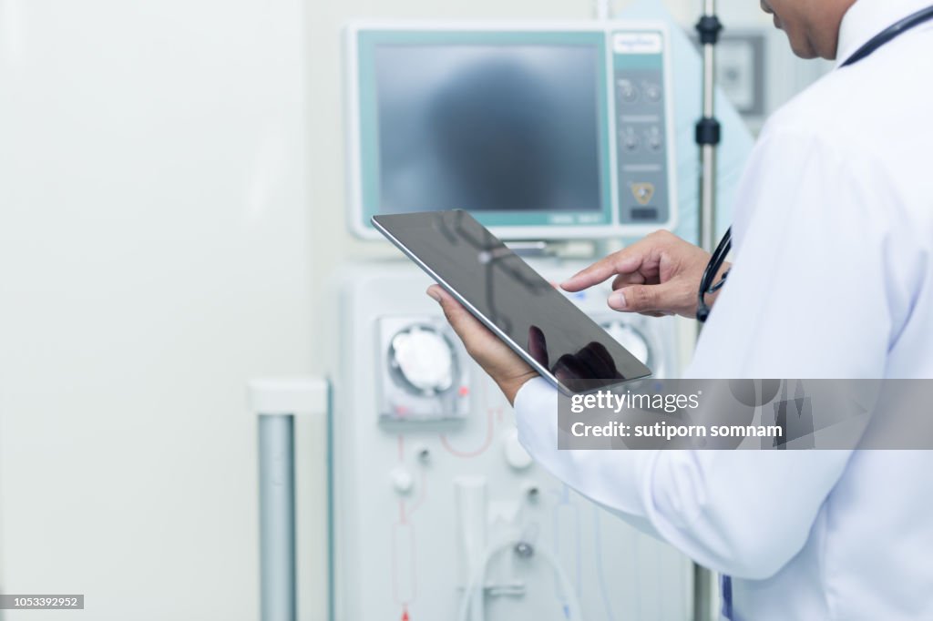 Medical care and healthcare Young doctor use tablet checking and touch about equipment medical dialysis machine