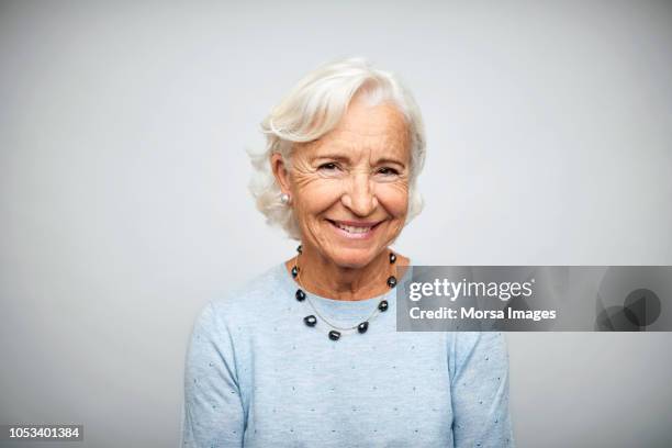 elderly businesswoman smiling on white background - aged man portrait studio stock-fotos und bilder