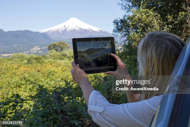 vrouw neemt foto van vulkaan met tablet uit auto - pucon stockfoto's en -beelden