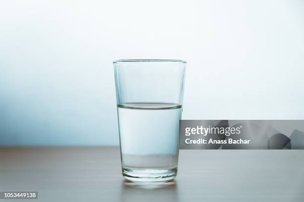 glass of water on table against wall - drinking glass stock pictures, royalty-free photos & images