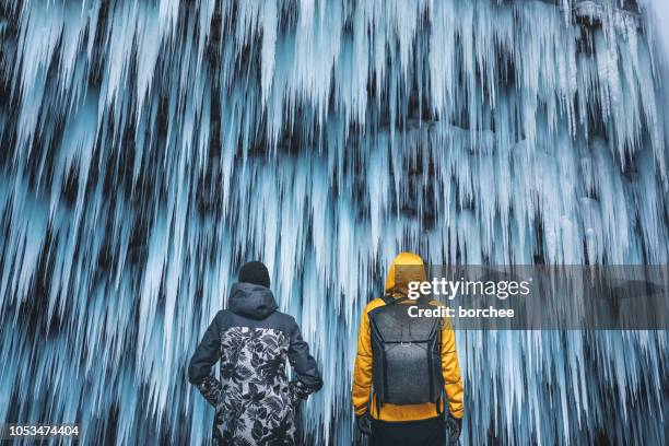 couple admiring the frozen waterfall - frozen waterfall stock pictures, royalty-free photos & images