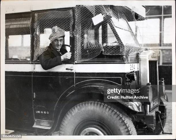 Mr Burnett, a voluntary driver during United Counties busmen's strike, is protected by metal netting around his driving cabin, Northamptonshire. The...