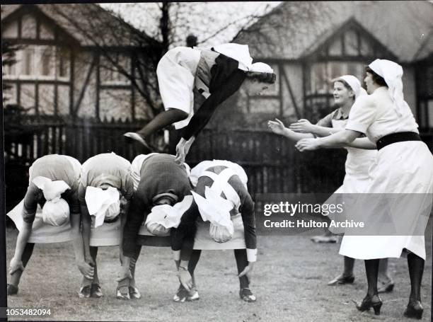 Mobile Unit and Red Cross nurses at an ARP centre in Southgate keep warm and keep fit with a game of leapfrog, England, World War II. This Red Cross...