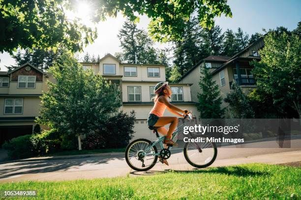 tween girl biking on sidewalk in residential neighborhood - american girl alone stock-fotos und bilder
