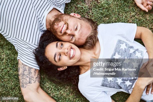 coppia multietnica sdraiata sull'erba nel cortile sul retro - ritratto coppia mista foto e immagini stock