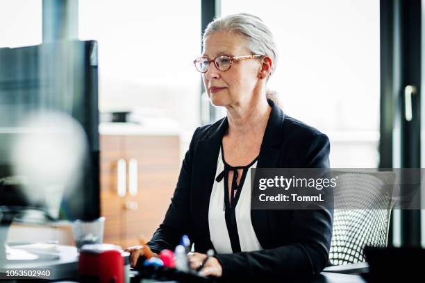 mature business owner working at computer - economy business and finance stock pictures, royalty-free photos & images