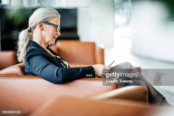 mature business owner relaxing at office - businesswoman hotel stock pictures, royalty-free photos & images