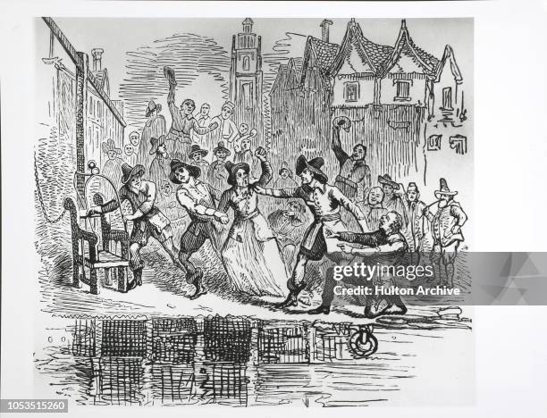 An old woman is dragged to the ducking stool at the river at Ipswich, Suffolk. The ducking stool was a chair in which people were restrained and...