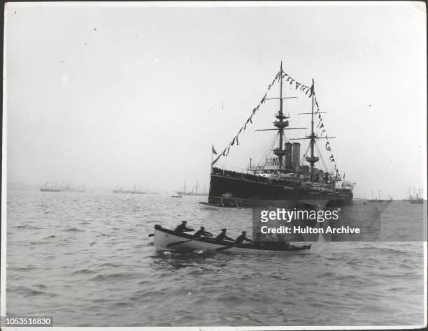 Ships of the Royal Navy decked with flags and a rowing boat full of sailors during a naval review at Spithead, in celebration of Queen Victoria's...