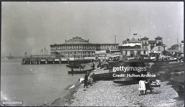 Boats on the beach at Southsea, England, with advertisements for Bovril and Oxo on a building behind, 1896.