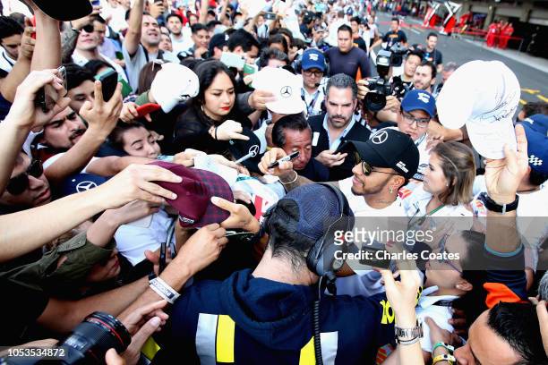 Lewis Hamilton of Great Britain and Mercedes GP signs autographs for fans in the Pitlane during previews ahead of the Formula One Grand Prix of...
