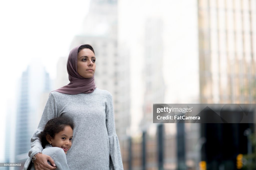 Muslim mother and child hug in the city