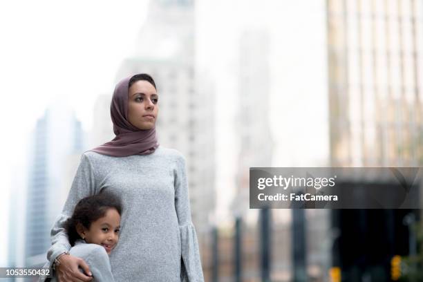 muslim mother and child hug in the city - migrant mother stock pictures, royalty-free photos & images