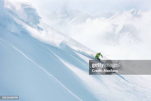 mann einen abhang hinunter auf frischem schnee skifahren - freeride stock-fotos und bilder