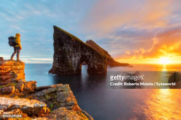 trekker admires drangarnir rock, faroe islands - îles féroé photos et images de collection