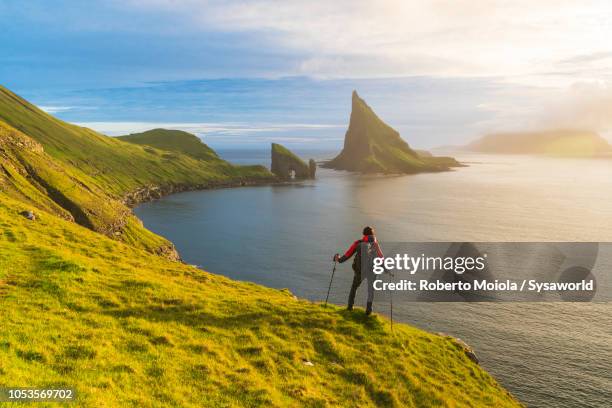 trekker admires drangarnir rock, faroe islands - faroe islands stockfoto's en -beelden