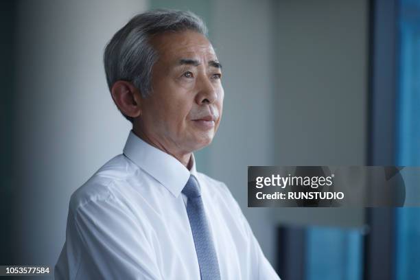 pensive senior businessman looking away - asian ceo stock-fotos und bilder