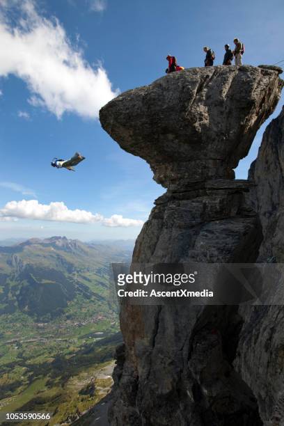 base jumper/ wingsuiter launches off cliff in the alps - base jumping stock pictures, royalty-free photos & images