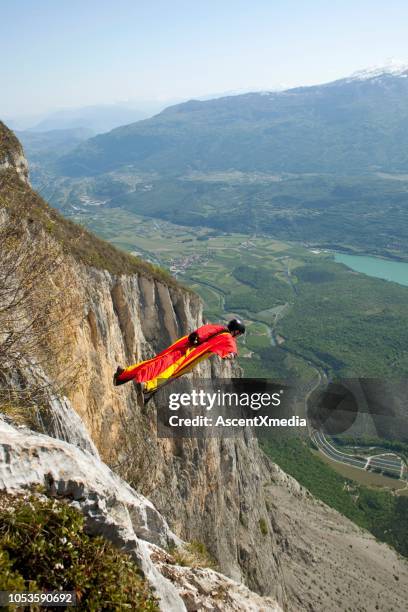 wingsuiter launches off cliff over the swiss alps - cliff jumping stock pictures, royalty-free photos & images