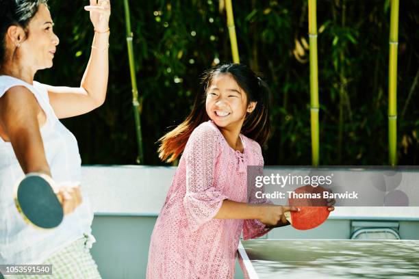 smiling young girl playing table tennis with aunt outdoors on sunny afternoon - indian aunt stock pictures, royalty-free photos & images