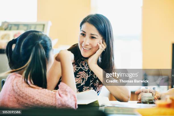 smiling mother in discussion with daughter while doing homework in kitchen - indian mother daughter stock-fotos und bilder