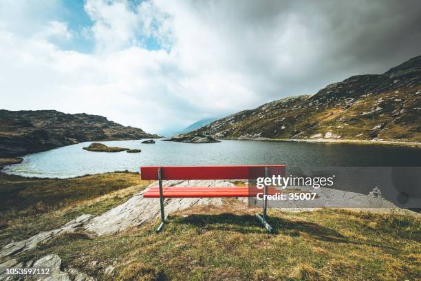 rode bankje met een weergave, mountain lake san bernardino, zwitserland - franken stockfoto's en -beelden