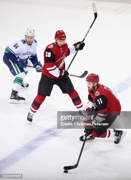 Brendan Perlini of the Arizona Coyotes sktates with the puck past Dylan Strome and Tyler Motte of the Vancouver Canucks during the second period of...