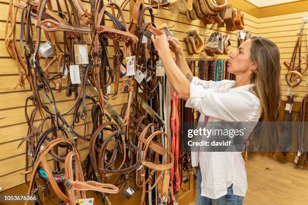 vrouw winkelen voor paard apparatuur in een zadel-winkel - paardrijbenodigdheden stockfoto's en -beelden