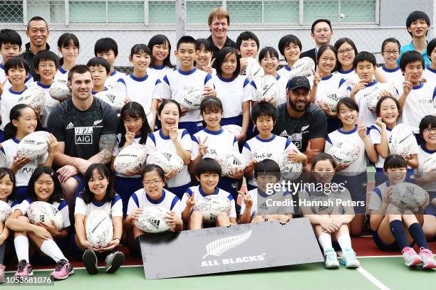 Liam Squire, Patrick Tuipulotu and Vaea Fifita pose for a photo with children during a New Zealand All Blacks visit the Shiba Elementary School on...