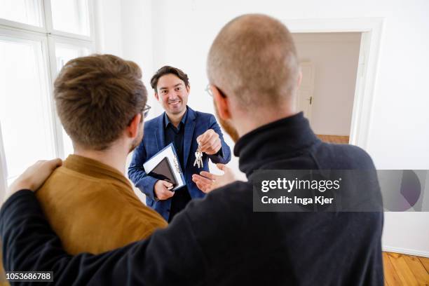 Posed scene on the topic of property market. A estate agent hands flat keys to a gay couple on October 25, 2018 in Berlin, Germany.