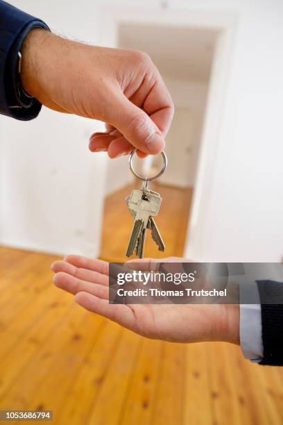 Posed scene on the topic of handing over an apartment. A estate agent hands flat keys in an empty apartment on October 25, 2018 in Berlin, Germany.