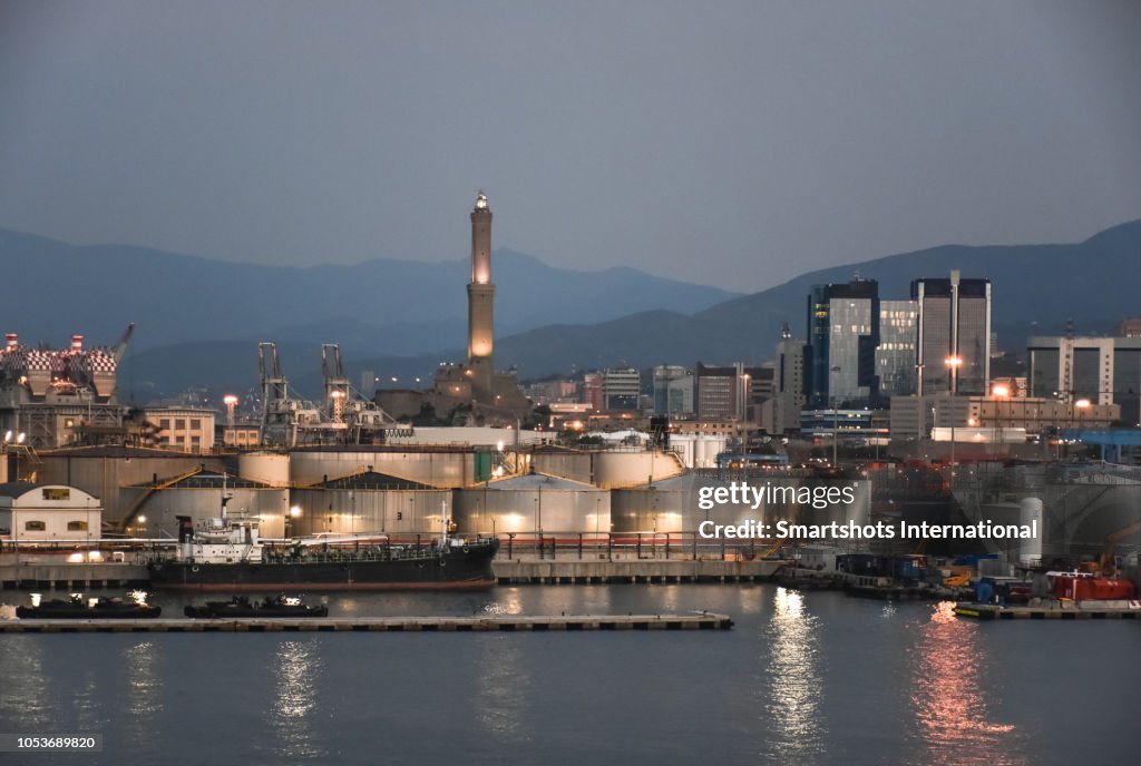 Dawn at Genoa's commercial port with Lanterna lighthouse illuminated on background in Genoa, Italy
