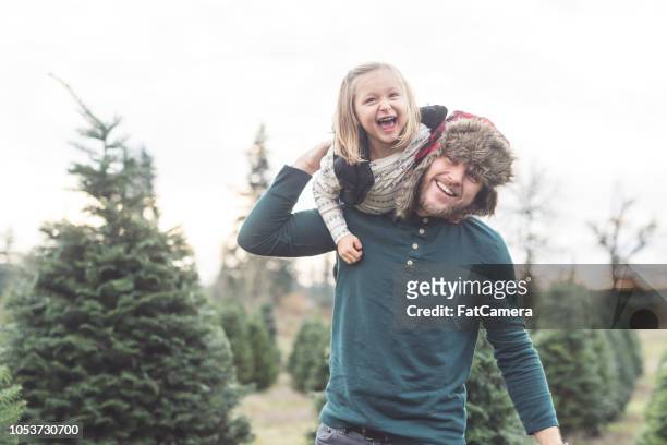 dad playfully carries his daughter around at a christmas tree farm - november 2 2017 stock pictures, royalty-free photos & images