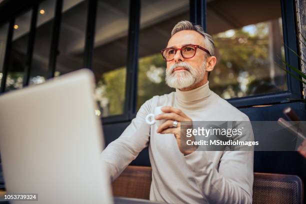 handsome mature adult using laptop. - bar drink establishment stock pictures, royalty-free photos & images
