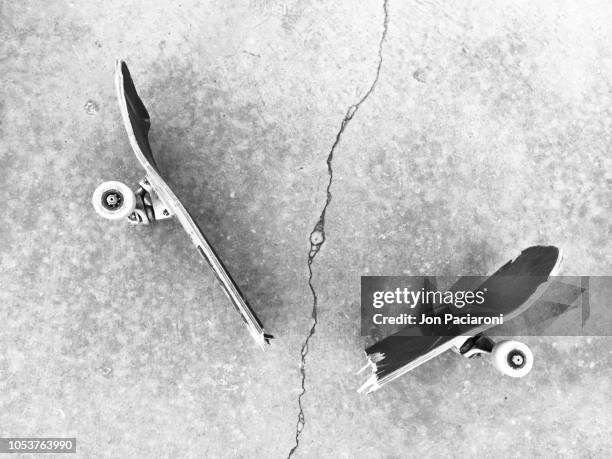 broken skateboard on a sidewalk crack. - monopatín artículos deportivos fotografías e imágenes de stock