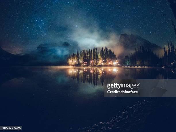 emerald lake with illuminated cottage under milky way - canada background stock pictures, royalty-free photos & images