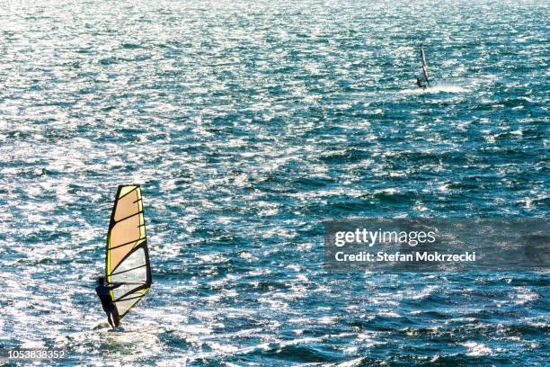 recreational windsurfers enjoying a summer weekend - windsurfbrett stock-fotos und bilder