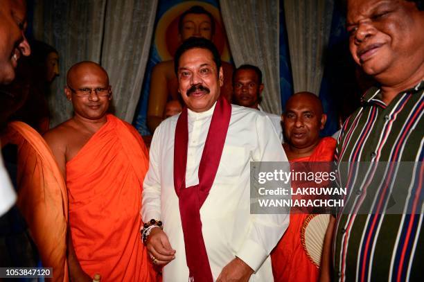 Sri Lanka's former president and new prime minister Mahinda Rajapaksa receives blessings from a Buddhist monk as he offers prayers at a temple after...