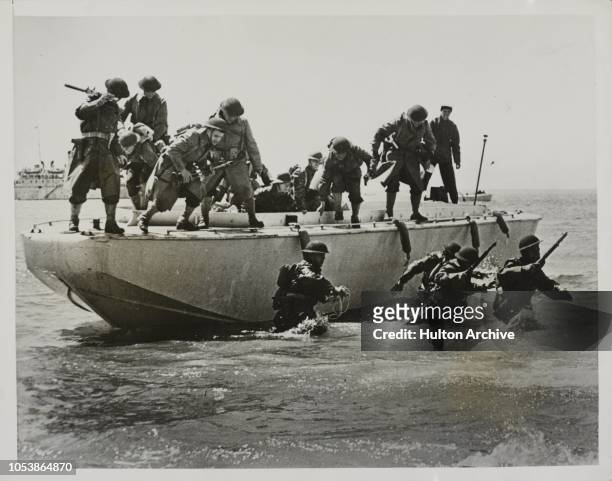 Troops In Training, A striking picture as troops of the U.S. Army leap from the specially designed and constructed 'Y' boat which carried them a...