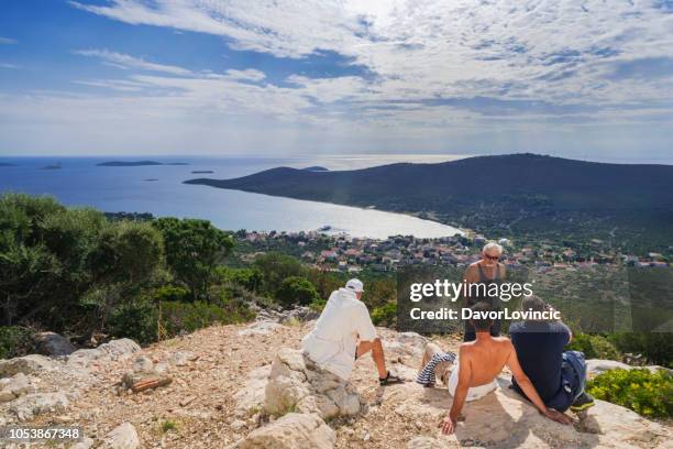 tourists, two seniors and two adult man, resting on the top of island ist while enjoying wonderful panoramic view of island ist in adriatic archipelago, croatia - kroatien zadar stock pictures, royalty-free photos & images