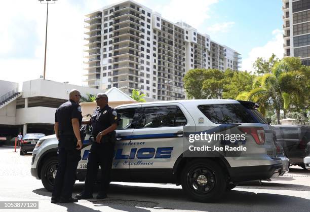 Aventura City police officers stand across the street from the condo building that has a possible connection to alleged bomber Cesar Sayoc and his...